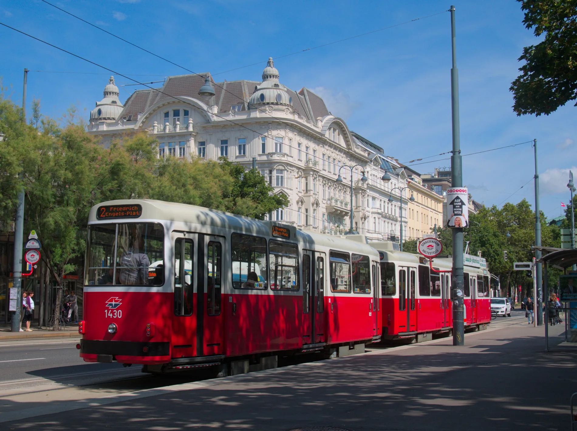 Rote Straßenbahn vor historischen Wiener Wohn- und Geschäftshäusern